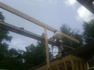Carpenter setting a ridge beam over a new addition frame — Ice Dam Removal by Roofing Brothers in Trufant