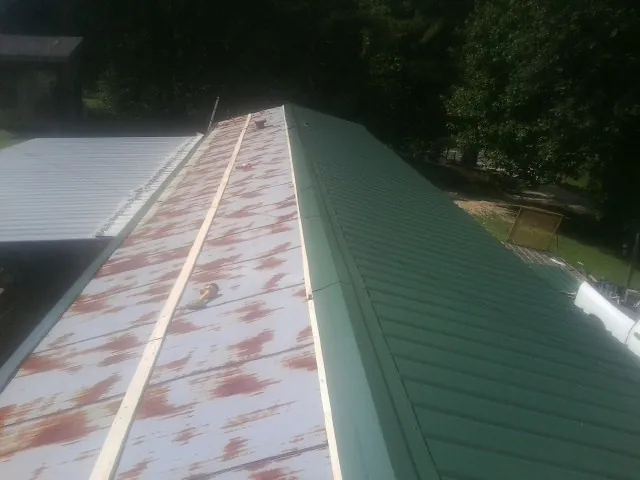 Old rusted panels beside newly installed green metal roofing — Wind Damage Roof Repair by Roofing Brothers in Trufant