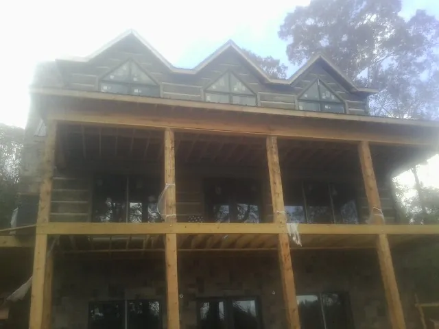 Dormers and porch framing on a large log home under construction — Roof Coating work by our crew in Trufant
