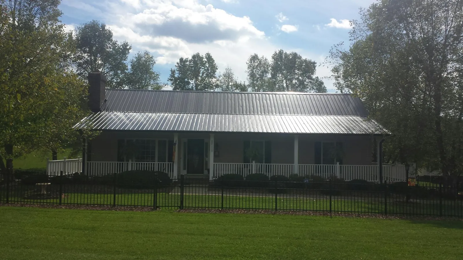 Gray metal roof on a brick ranch with a full width front porch — Gutter Guard Installation work by our crew in Trufant