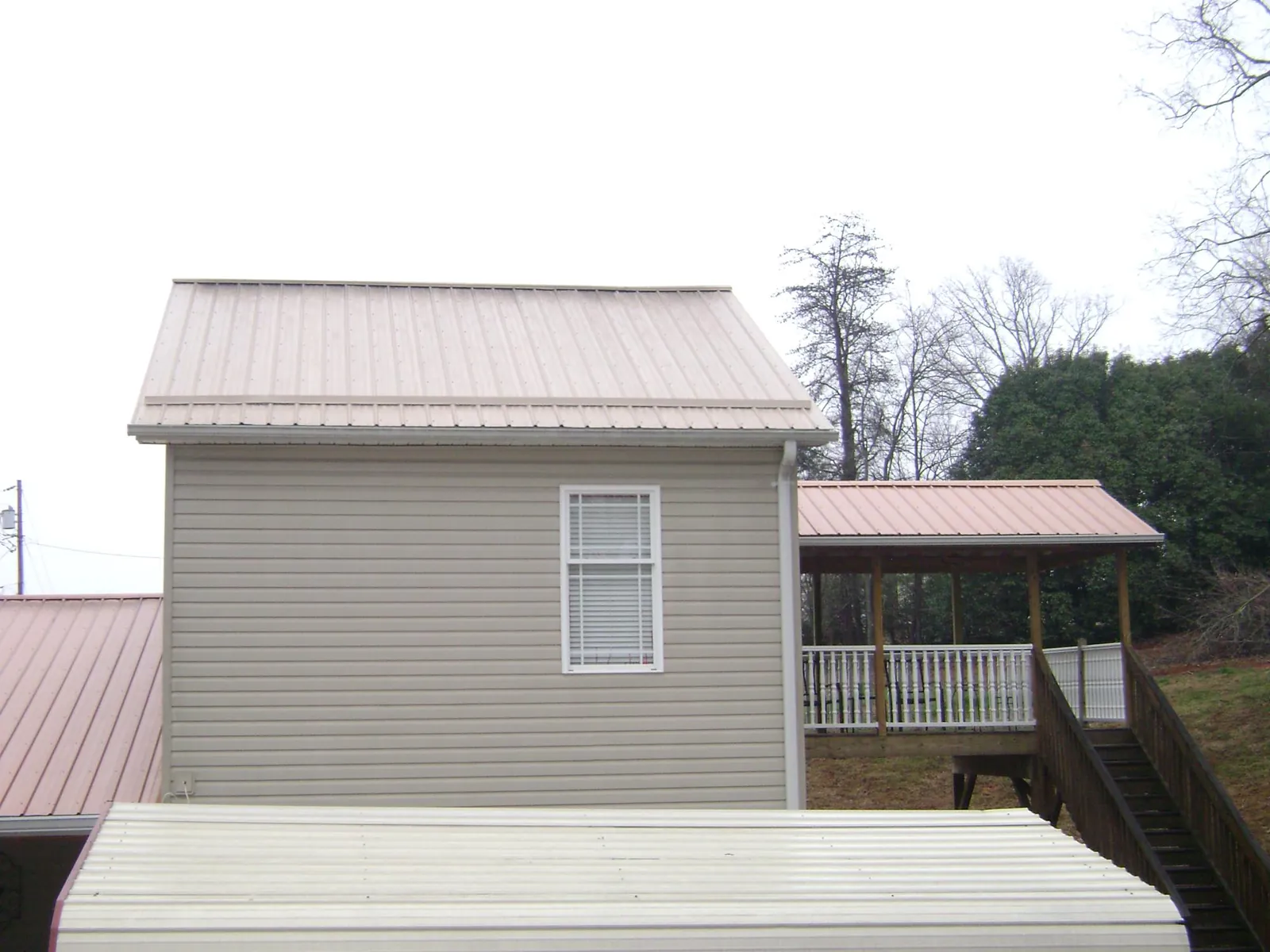 Tan metal roofs on a two story addition and attached porch, from a Roof Replacement job in Trufant